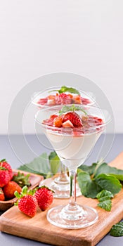 Delicous and nutritious double color colour strawberry desserts with mint and diced sarcocarp topping isolated with airy blue