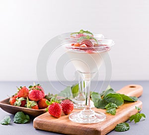 Delicous and nutritious double color colour strawberry desserts with mint and diced sarcocarp topping isolated with airy blue