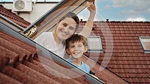 Delight of a mother and her son as they open attic windows and enjoy the view outside, illustrating the idea of family