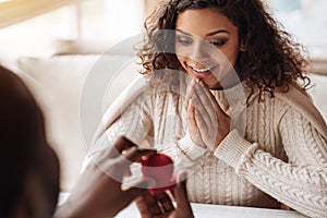 Delighted African American woman receiving the proposal in the cafe