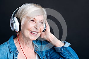 Delighted aged woman listening to music