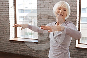 Delighted aging woman dancing in the ballroom