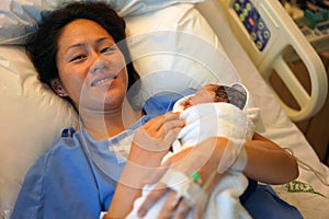 Delighted Asian Chinese woman holding her new born baby right after childbirth