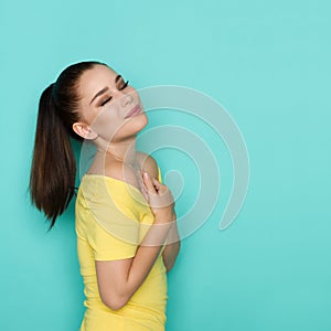 Delighted beautiful young woman with closed eyes is holding hands on chest