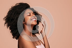 Delighted black woman enjoying skin cleanness