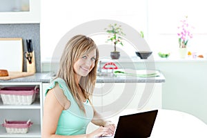 Delighted blond woman using her laptop and smiling