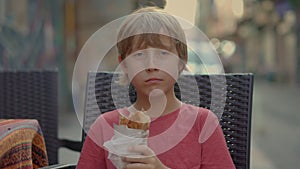 A delighted boy tourist savors the taste of Turkey, enjoying a freshly made balik ekmek wrap on the bustling streets of