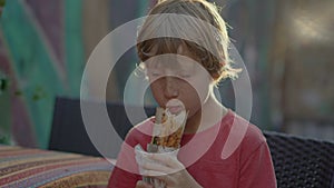 A delighted boy tourist savors the taste of Turkey, enjoying a freshly made balik ekmek wrap on the bustling streets of