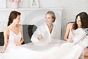 Delighted bride sitting with her bridesmaids on the bed