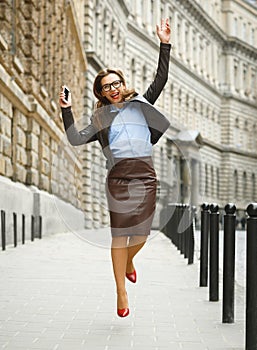 Delighted business woman jumping for joy while talking on the sm