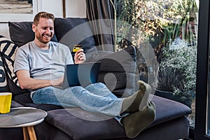 Delighted caucasian man, shopping with his credit card, online