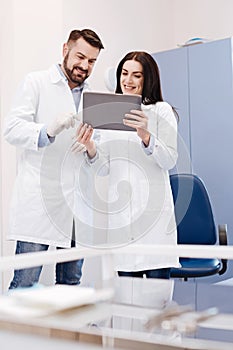 Delighted cheerful doctors looking at the tablet screen