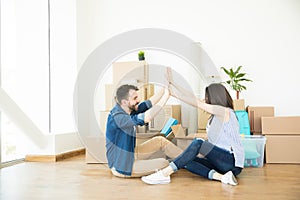 Delighted Couple Giving High-Five On Floor During Relocation