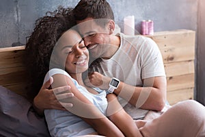 Delighted couple hugging each other in bed