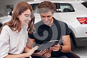 Delighted couple reading contract in dealership