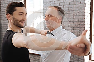 Delighted dance instructor teaching aged man at the ballroom