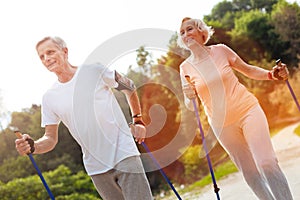 Delighted elderly couple practicing Nordic walking