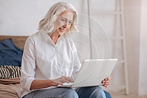 Delighted elderly woman holding a laptop