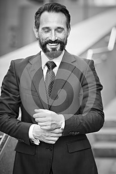 Delighted entrepreneur keeping his eyes closed while touching his shirt sleeves. Black and white photo of happy