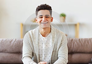 Delighted ethnic guy resting on couch