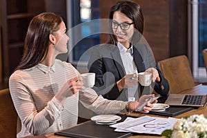 Delighted female colleagues drinking tea in an office