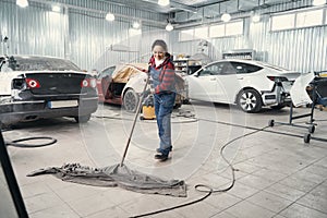 Delighted female person cleaning floor in the workshop