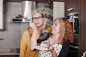 Delighted girlfriends eating cake in the kitchen