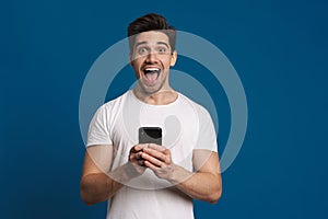 Delighted guy expressing surprise while using mobile phone