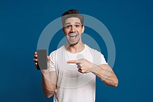 Delighted guy showing and pointing finger at mobile phone