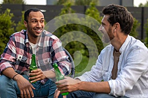 Delighted guys friends drinking beer and communicating at backyard party