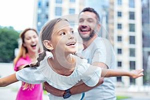 Delighted happy girl playing with her parents