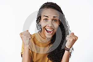 Delighted happy lucky african american girl receiving promotion feeling thrilled and satisfied clenching fists in