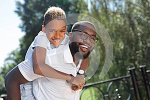 Delighted happy man carrying his son on the back