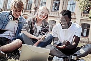 Delighted happy students sitting on the grass