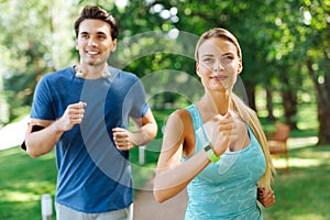 Delighted joyful couple jogging in the park together