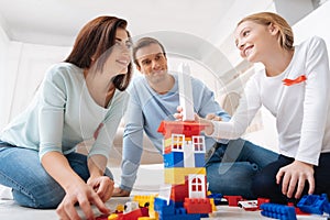 Delighted joyful family playing with construction blocks