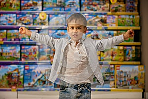 Delighted little boy child standing with toys showcases behind back