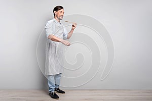 Delighted man in an apron holding a spoon