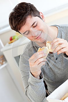 Delighted man eating bread in the kitchen