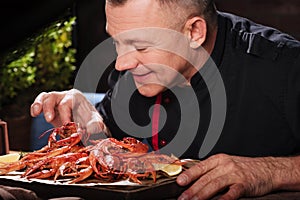 Delighted man eating crayfishes in restaurant