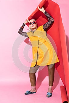 Delighted mature female standing over pink background