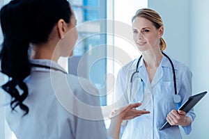 Delighted medical worker listening her assistant