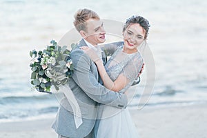 Delighted newly-weds cuddling at the seashore