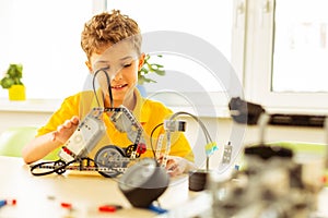 Delighted nice boy enjoying the process of robot construction