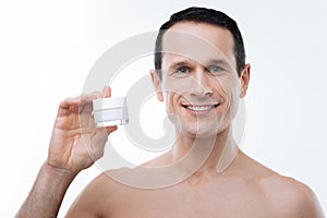 Delighted nice man using facial cosmetics
