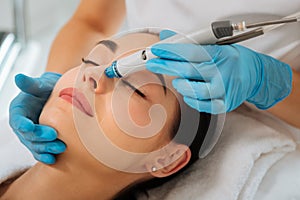 Delighted nice positive woman having hydrafacial procedure