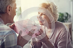 Delighted old woman accepting gift from man