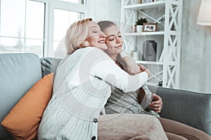 Delighted positive aged woman hugging her granddaughter