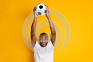 Delighted positive cheerful afro american guy hold football ball celebrate national team goal world cup match wear white