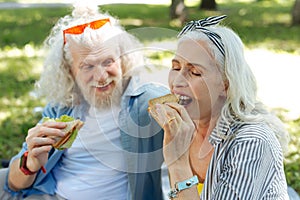 Delighted positive woman biting a sandwich